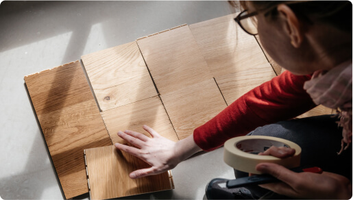 A woman is comparing flooring samples.